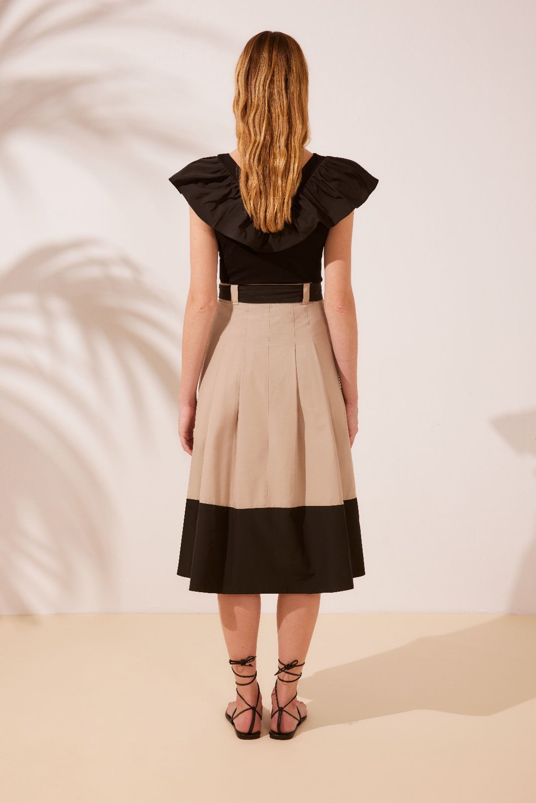 ARGGIDO - MAGLIA NERA CON SCOLLO A V E AMPIO VOLANT CHE INCORNICIA LE SPALLE, REGALANDO UN TOCCO ROMANTICO E SOFISTICATO.